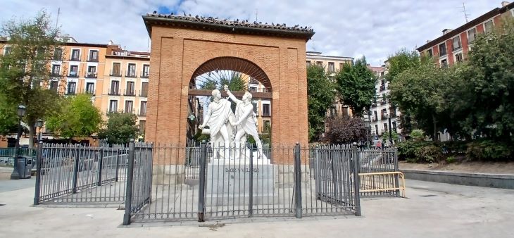Monumento a Daoíz y Velarde en la Plaza del Dos de Mayo, en el corazón del barrio de Malasaña, rodeado de edificios históricos y árboles.
