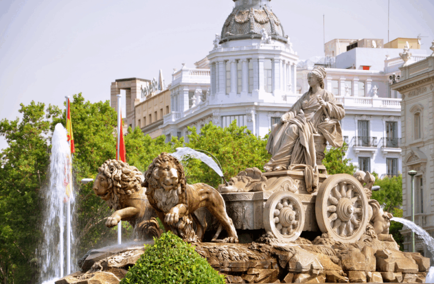 Fuente de Cibeles en Madrid con la figura de la diosa y los leones, frente a edificios históricos bajo un cielo claro.