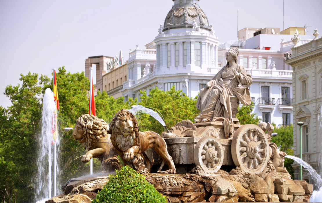 Fuente de Cibeles en Madrid con la figura de la diosa y los leones, frente a edificios históricos bajo un cielo claro.
