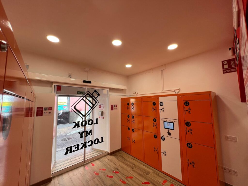 Interior de un local con taquillas inteligentes naranjas para guardar equipaje en Madrid.
