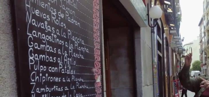 Pizarra con la carta de tapas en la entrada de una taberna tradicional madrileña, en una calle típica del centro de Madrid.