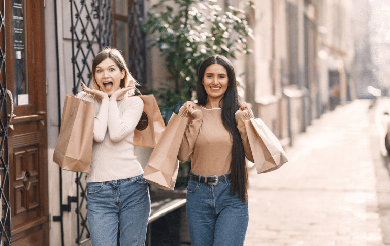 Dos personas caminando por una calle del centro con bolsas de compras tras una jornada de shopping.