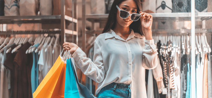 Persona sosteniendo varias bolsas de compras en el interior de una tienda de moda.